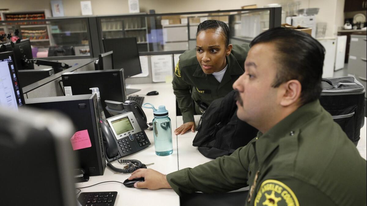 L.A. County Sheriff’s custody assistants Alexis Herbert, left, and Victor Gamont screen requests from ICE to take custody of inmates.