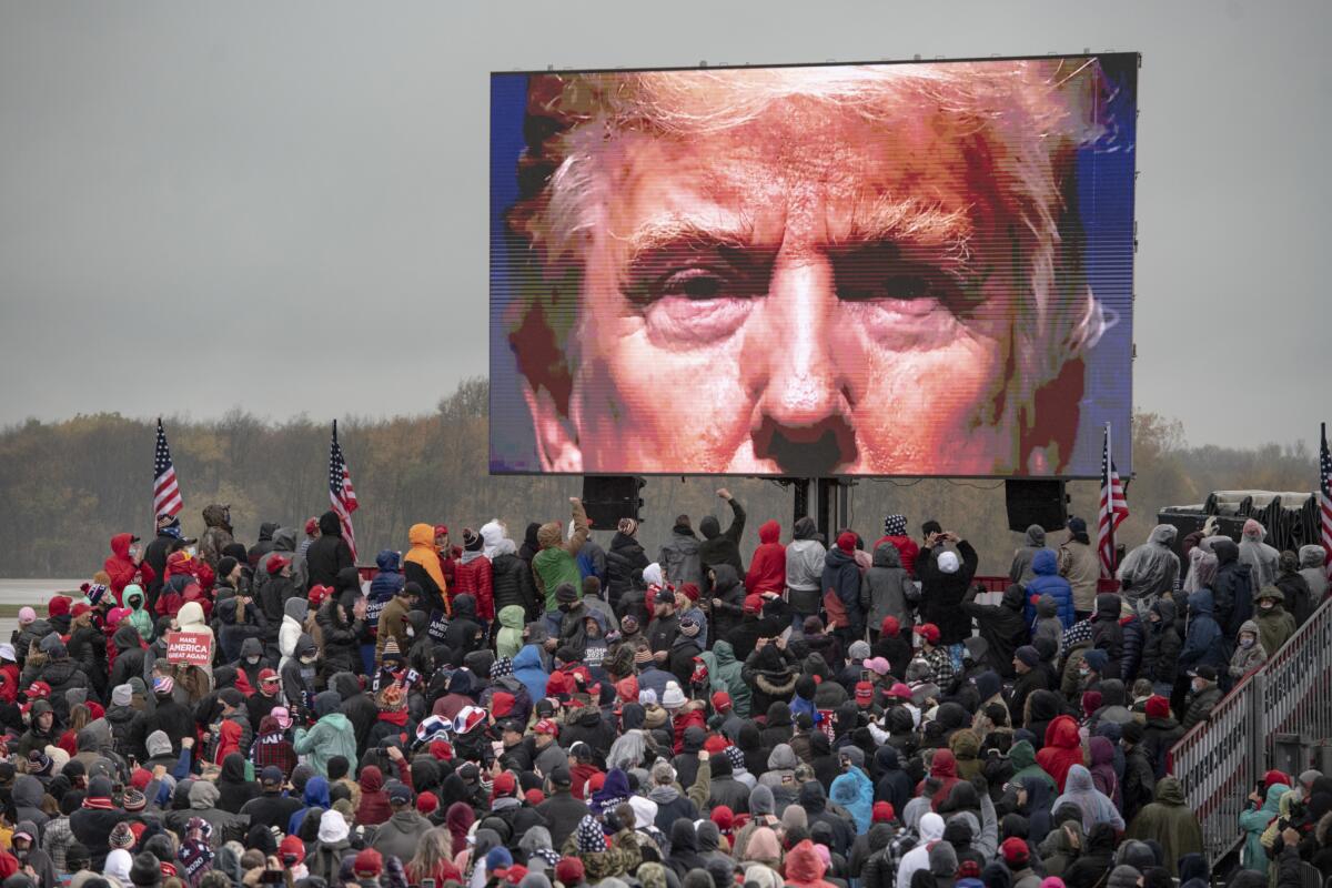 Partidarios del presidente Donald Trump miran una pantalla de video en un evento de campaña