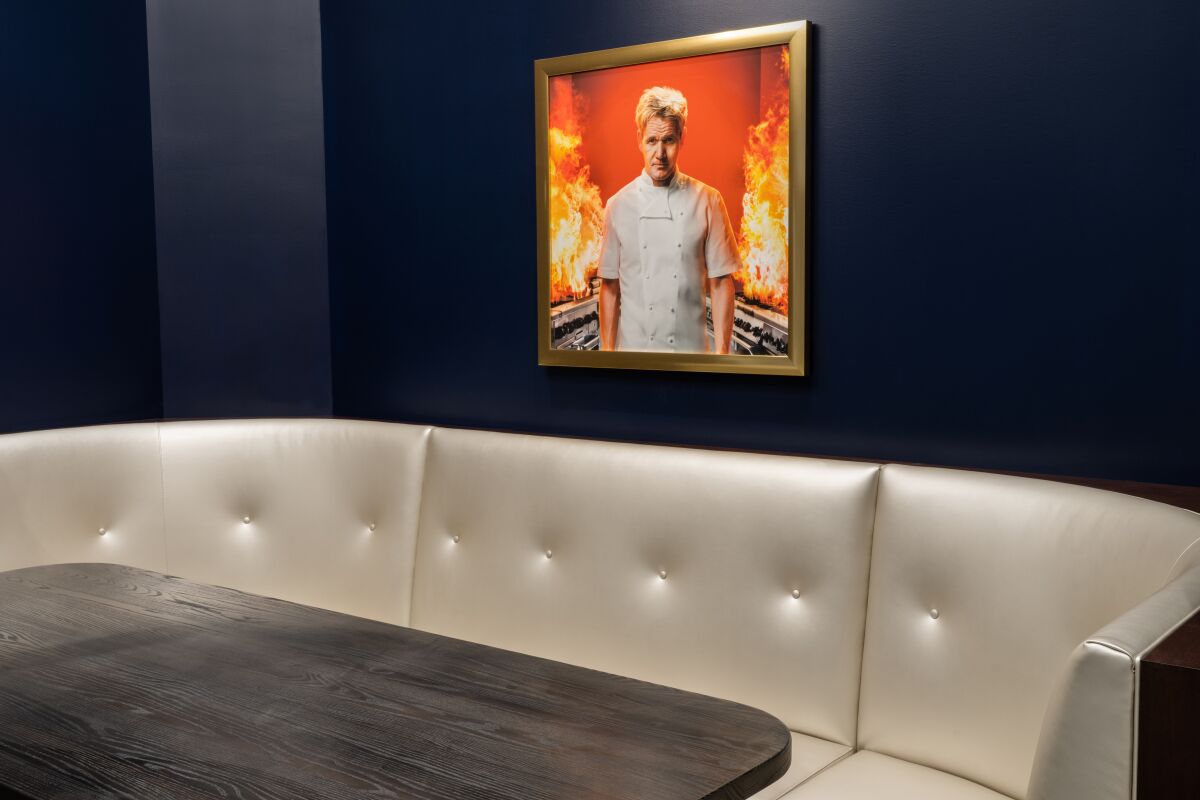 A framed portrait of Gordon Ramsay hangs over a banquette at Hell's Kitchen restaurant.