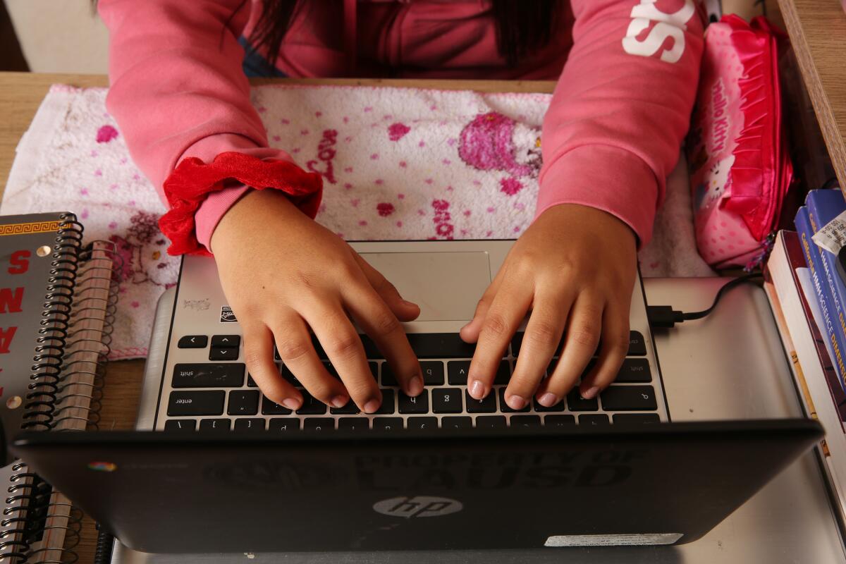 A picture of a young girl's hands on a laptop keyboard.