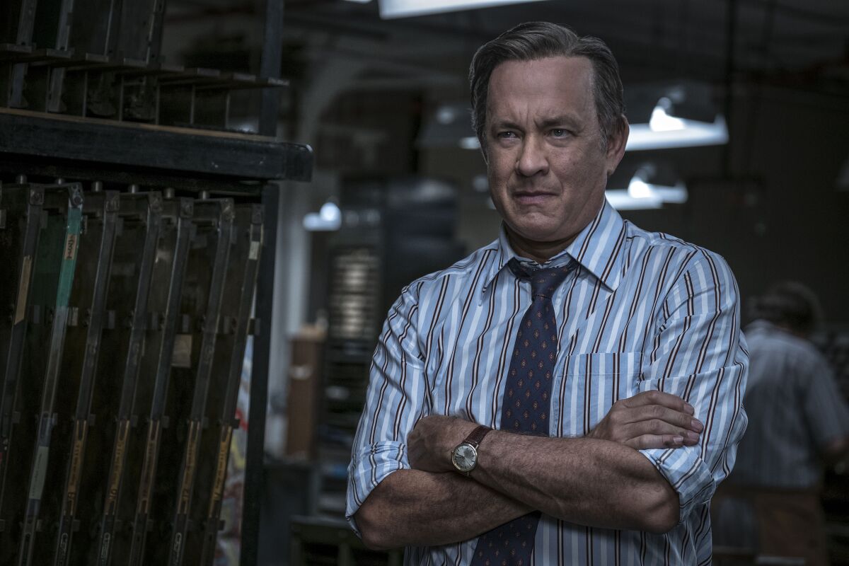 A man in a striped shirt and tie folds his arms in the movie "The Post."