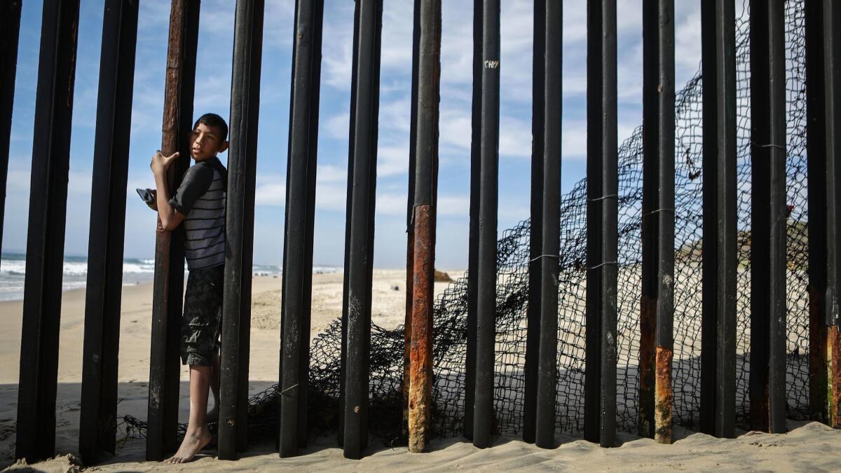 A boy walks between the border fence on the beach at the U.S.-Mexico border in Tijuana on April 5.