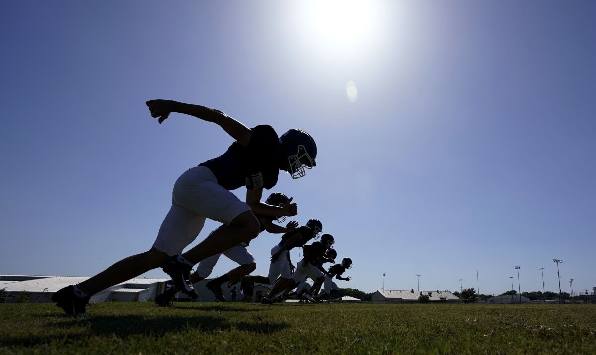 Thrall High School football players, wearing face masks at all times and using social distancing when possible, go through a practice, Thursday, Aug. 13, 2020, in Thrall, Texas. Texas will play high school football this fall, but some of it will be delayed, fans will be limited and masks will be required as the state continues to fight a surge in new coronavirus cases. (AP Photo/Eric Gay)