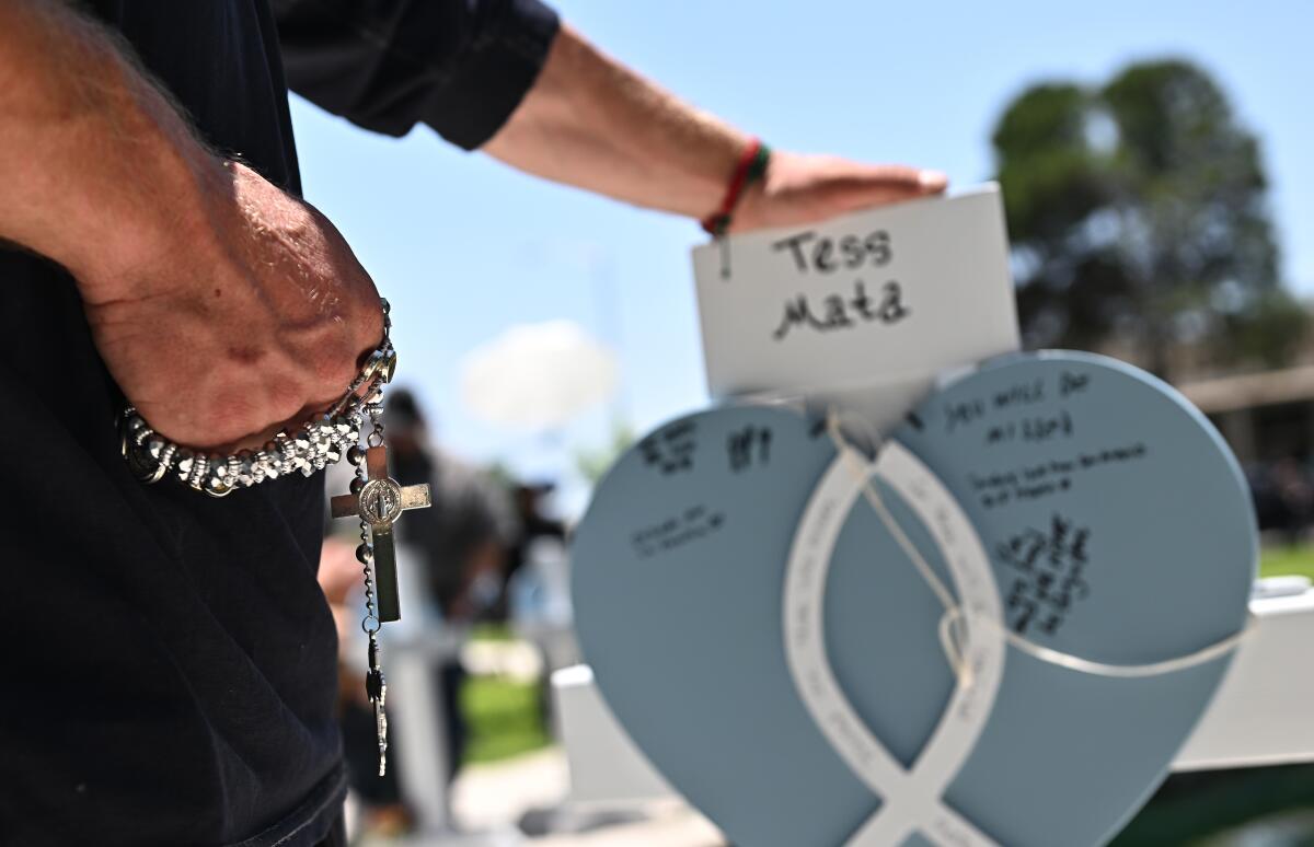 A man holding touches a personalized memorial for one of the victims of the Uvalde, Texas, shooting.