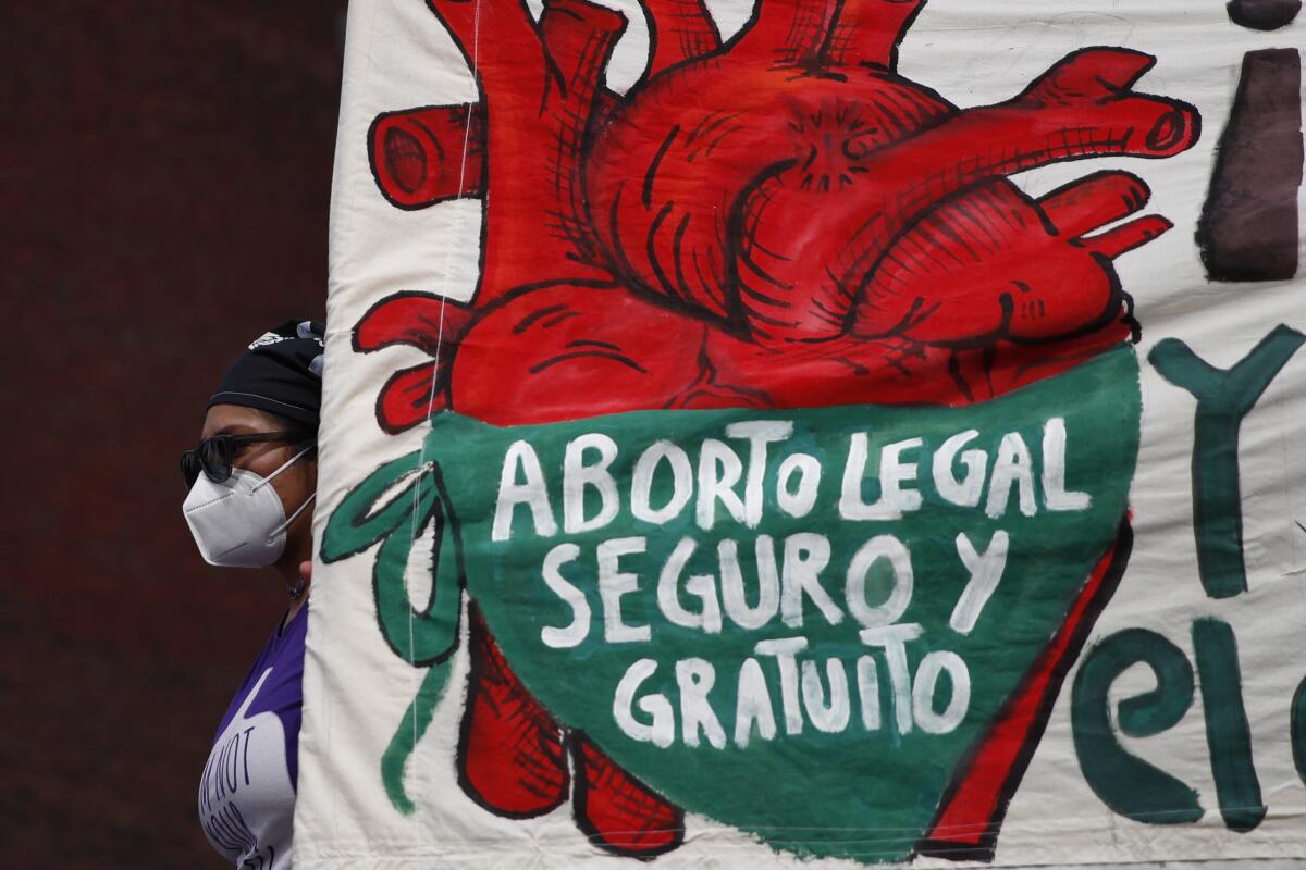 A woman holds a banner reading in part, in Spanish, "Abortion Safe and Legal" during a demonstration