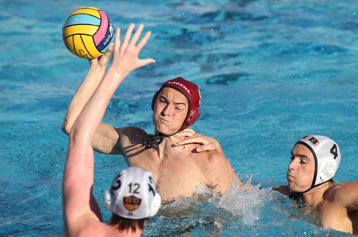 Laguna Beach's James Nolan takes a shot and scores as Huntington Beach's Ethan Crooks (4) and Tyler Padua surround him in a Surf League match on Wednesday at Corona del Mar High.