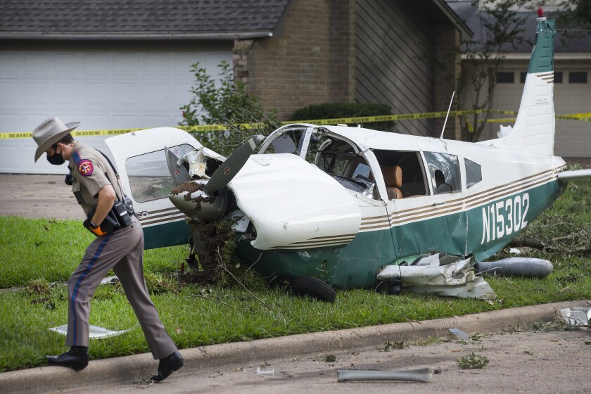 FILE - A law enforcement officer works at the site of the crash of a plane, in the front yard of a home Tuesday, July 28, 2020 in Houston. U.S. crash investigators want the government to require owners of small planes to install carbon monoxide detectors. The National Transportation Safety Board made the recommendation Thursday, Jan. 20, 2022 to the Federal Aviation Administration. (Brett Coomer/Houston Chronicle via AP, File)