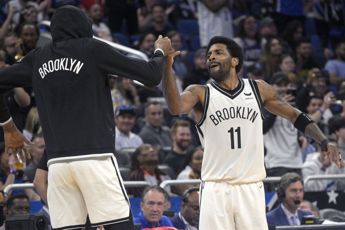 Brooklyn Nets guard Kyrie Irving (11) celebrates with forward Kevin Durant, left, after Irving scored his 60th point of the game in the second half of an NBA basketball game against the Orlando Magic, Tuesday, March 15, 2022, in Orlando, Fla. (AP Photo/Phelan M. Ebenhack)