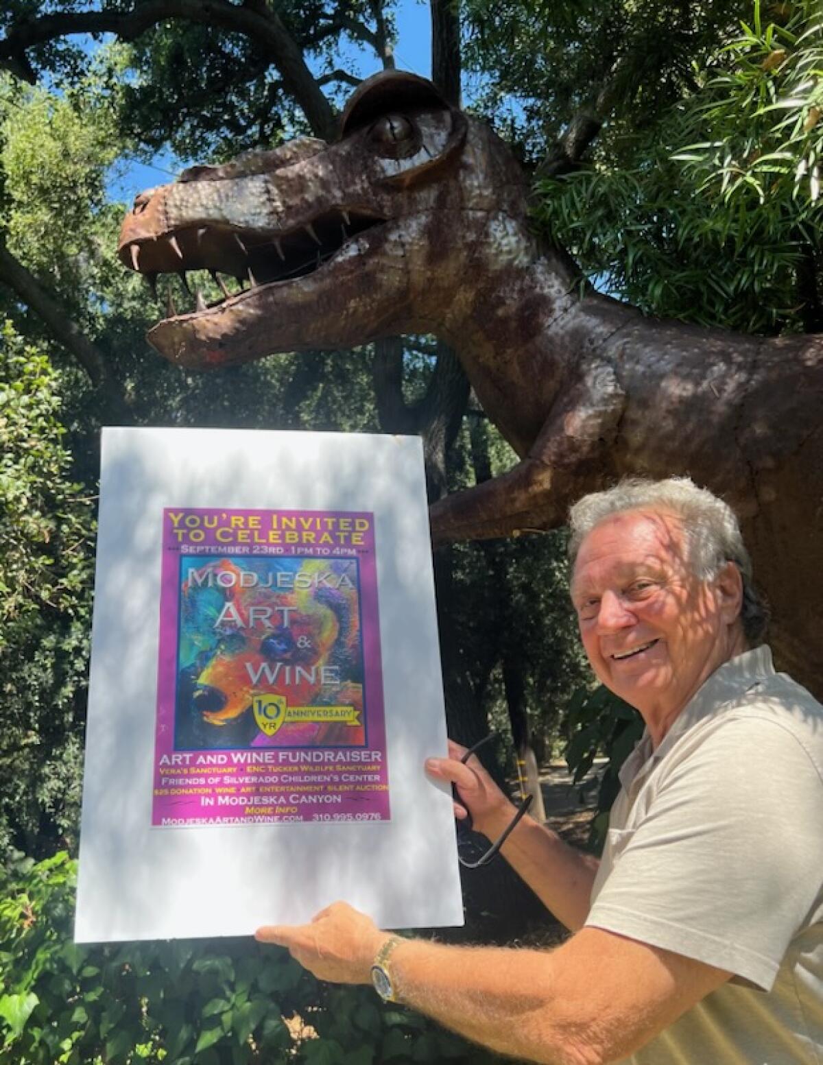 Greg Killingsworth poses with a poster and T-rex sculpture.