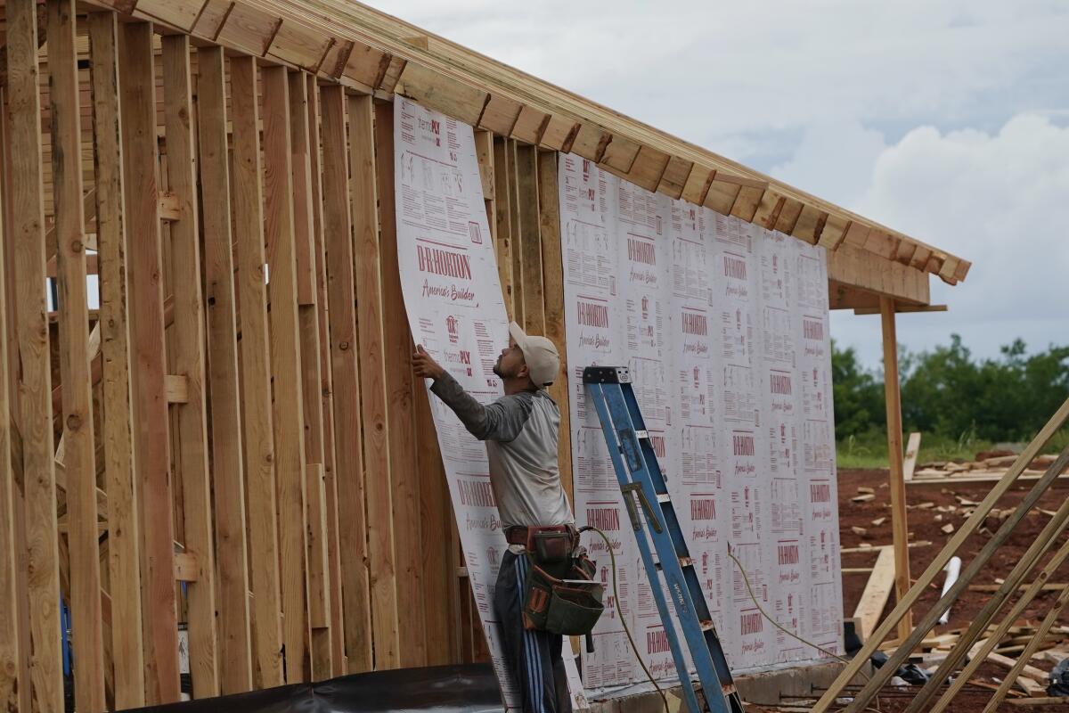 A worker installing insulation on a house under construction