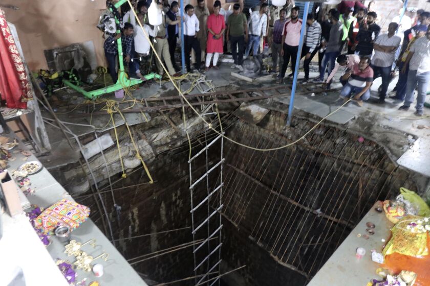 People stand around a structure built over an old temple well that collapsed Thursday as a large crowd of devotees gathered for the Ram Navami Hindu festival in Indore, India, Thursday, March 30, 2023. Up to 35 people fell into the well in the temple complex when the structure collapsed and were covered by falling debris, police Commissioner Makrand Deoskar said. At least eight were killed. (AP Photo)