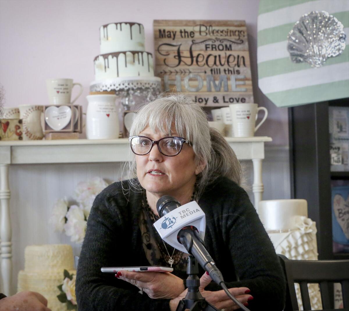 Cathy Miller speaks from her bakery, where a sign reads "May the blessings from heaven fill this home with joy and love."