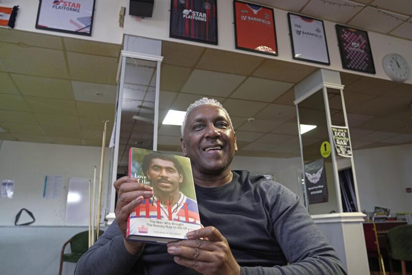 El exjugador de fútbol inglés Ricky Hill posa con una copia de su libro en Luton, Inglaterra para hablar de la falta de diversidad en puestos de entrenador el miércoles 20 de marzo del 2024. (AP Foto/Kin Cheung)