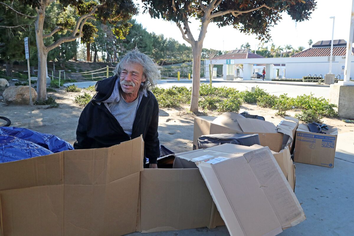 Gregory Scafferty, 62, sits in his cardboard bed in front of the Newport Transportation Center.