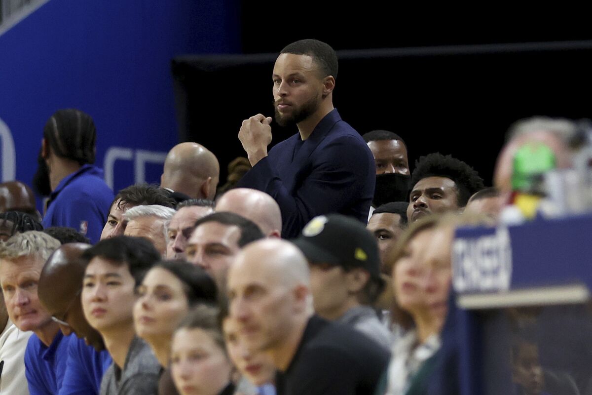 Golden State Warriors guard Stephen Curry, top, watches from the bench during the second half of an NBA basketball game against the San Antonio Spurs in San Francisco, Sunday, March 20, 2022. (AP Photo/Jed Jacobsohn)