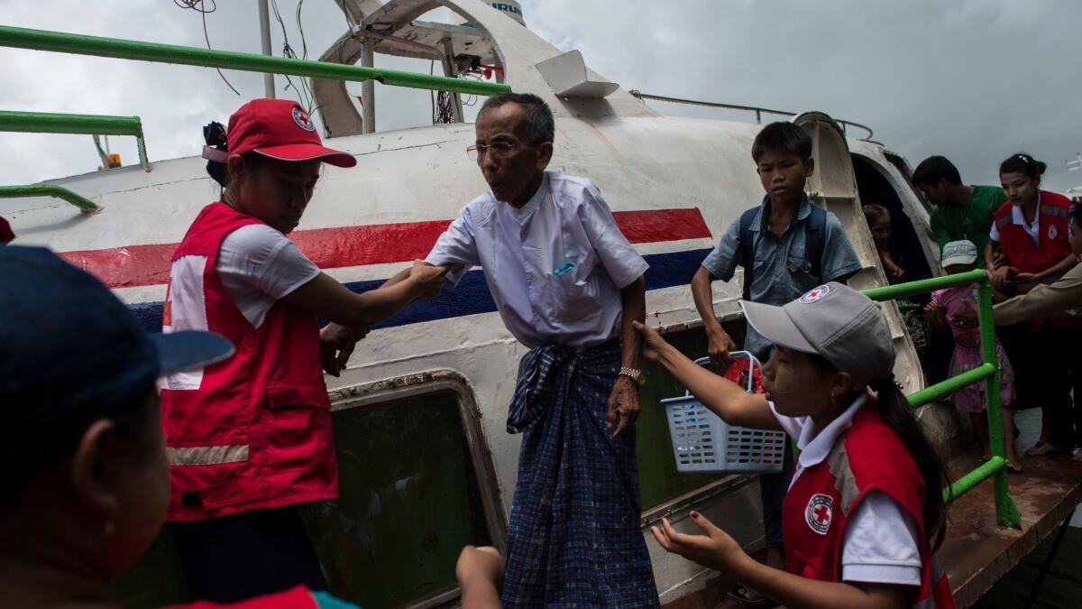 Members of Myanmar's Red Cross help people fleeing violence as they arrive Aug. 30 in Sittwe jetty, in Rakhine State, Myanmar.