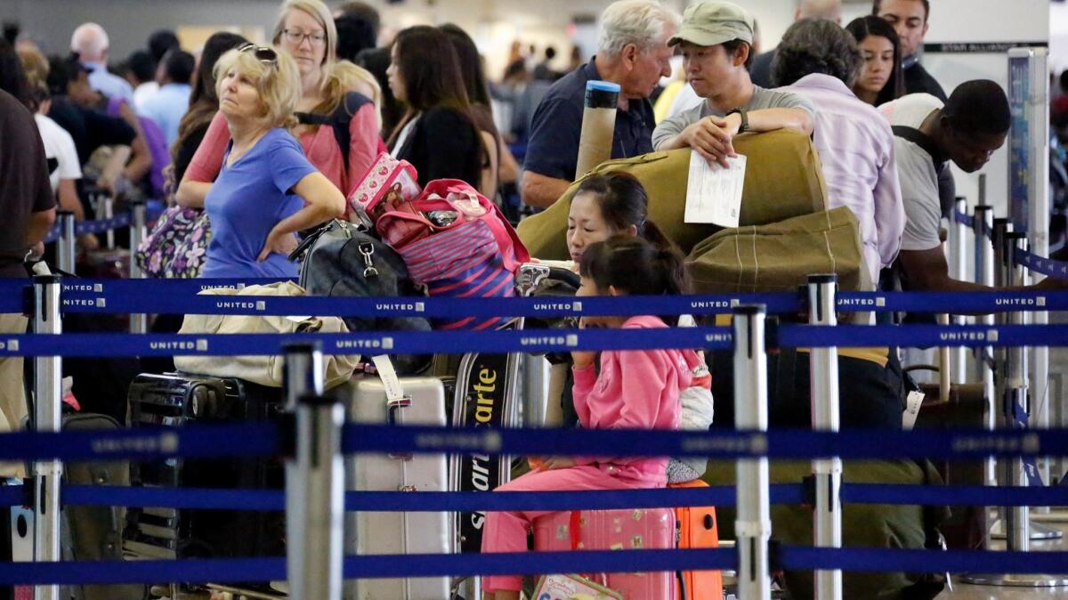 Passengers stand in a ticketing line at Los Angeles International Airport.