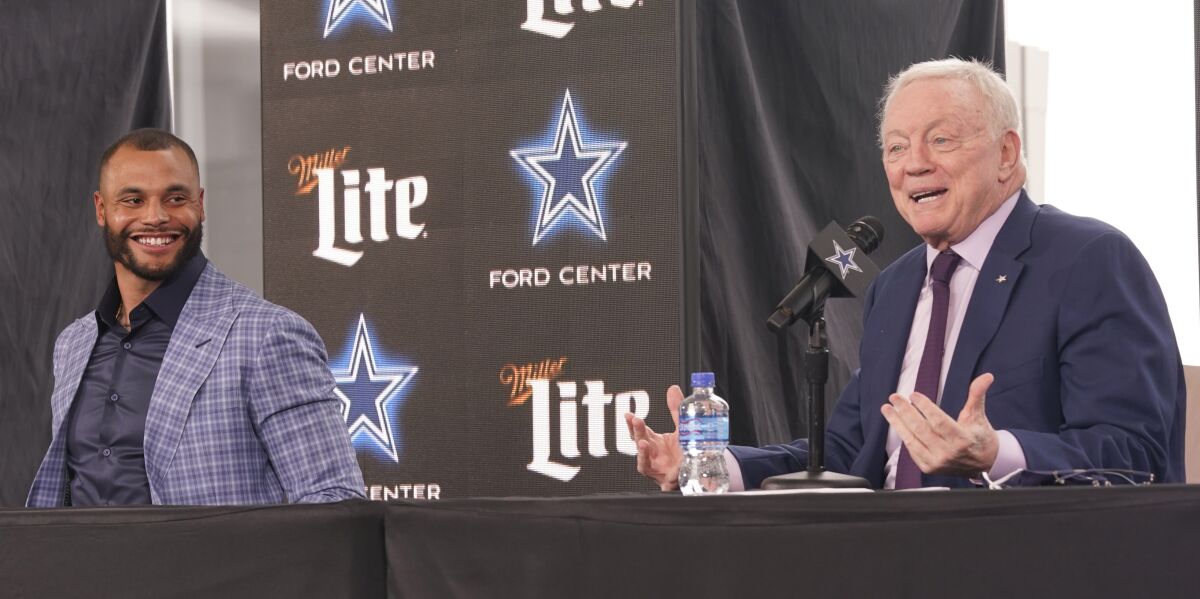 Dallas Cowboys quarterback Dak Prescott, left, looks on and smiles as team owner Jerry Jones speaks during a news conference.