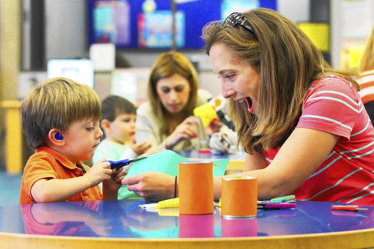John Thomas Stephenson, 2, of Glendale, with his mom Jennifer, who makes a face as he successfully cuts a green piece of paper, do arts and crafts in the Children's Room at the Glendale Central Library in Glendale on Friday, March 28, 2014. The Art Cart, which is available Friday's from 3:30 to 5:00, usually has an art project children can try to copy, or lots of supplies for them to be the creative artist that they are.