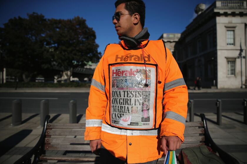A newspaper vendor wears a vest displaying front page of The Herald in Dublin, Ireland. Irish authorities were waiting for DNA test results in relation to a blond girl removed from a Roma family in Dublin, days after a similar case in Greece.