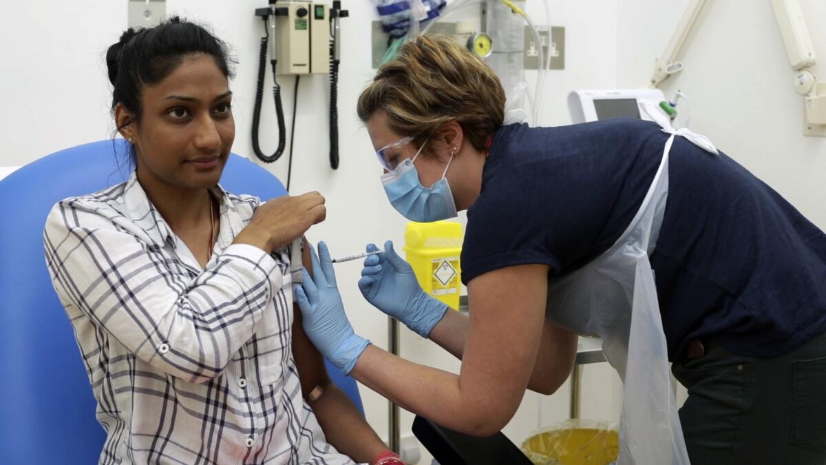 A volunteer in England participates in a clinical trial for an experimental COVID-19 vaccine. Trials like this are underway around the world.