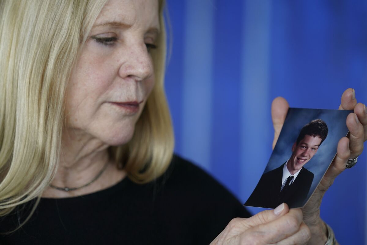 Dede Yoder poses for a picture with a photo of her son, Chris Yoder, after making a statement during a hearing in New York, Thursday, March 10, 2022. People who lost loved ones or years of their own lives to opioid addiction are getting their first and perhaps only chance to confront members of the Sackler family who own OxyContin maker Purdue Pharma. Thursday's virtual court hearing is being run by a U.S. Bankruptcy Court judge. (AP Photo/Seth Wenig)