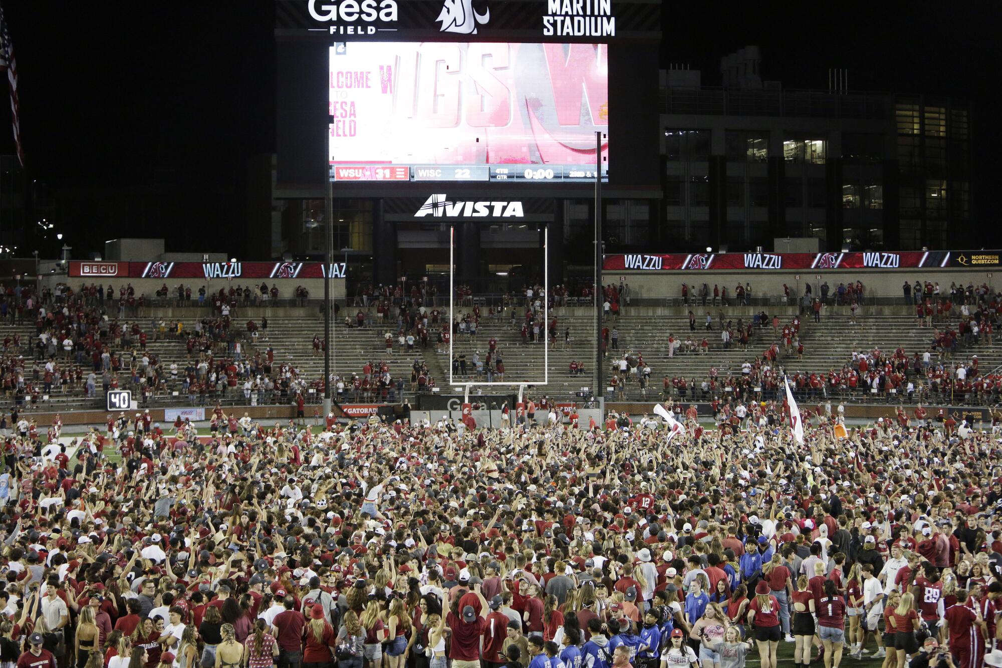 Washington State fans celebrate on the field after the Cougars' win over Wisconsin on Saturday.