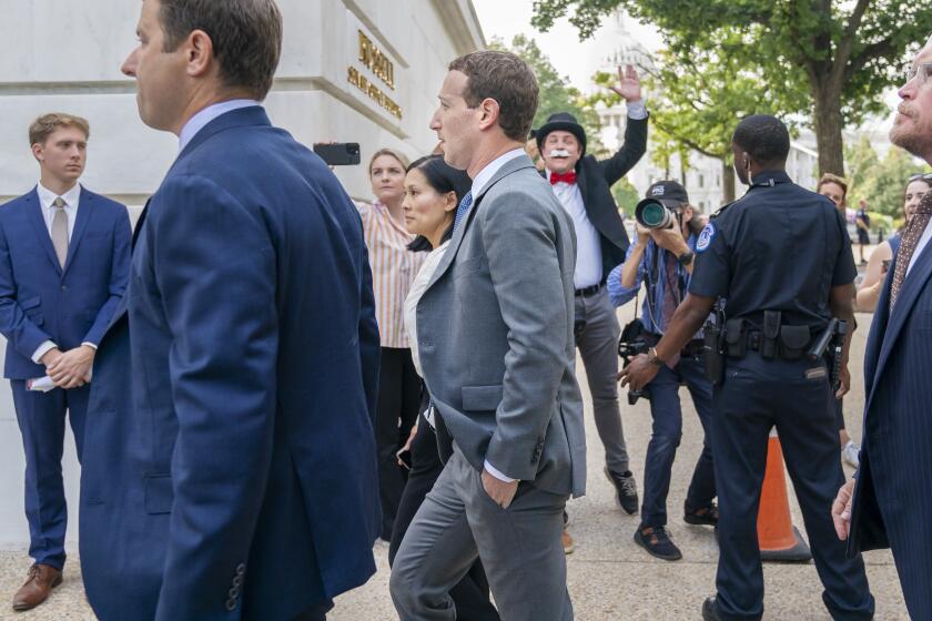 CORRECTS THAT THE WOMAN NEXT TO ZUCKERBERG IS NOT PRISCILLA CHAN - Meta CEO Mark Zuckerberg arrives for a closed-door gathering of leading tech CEOs to discuss the priorities and risks surrounding artificial intelligence and how it should be regulated, past a crowd of media and a protester dressed as the Monopoly Man, on Capitol Hill in Washington, Wednesday, Sept. 13, 2023. (AP Photo/Jacquelyn Martin)
