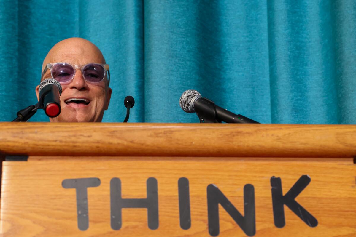 A smiling man peeks over a podium. 