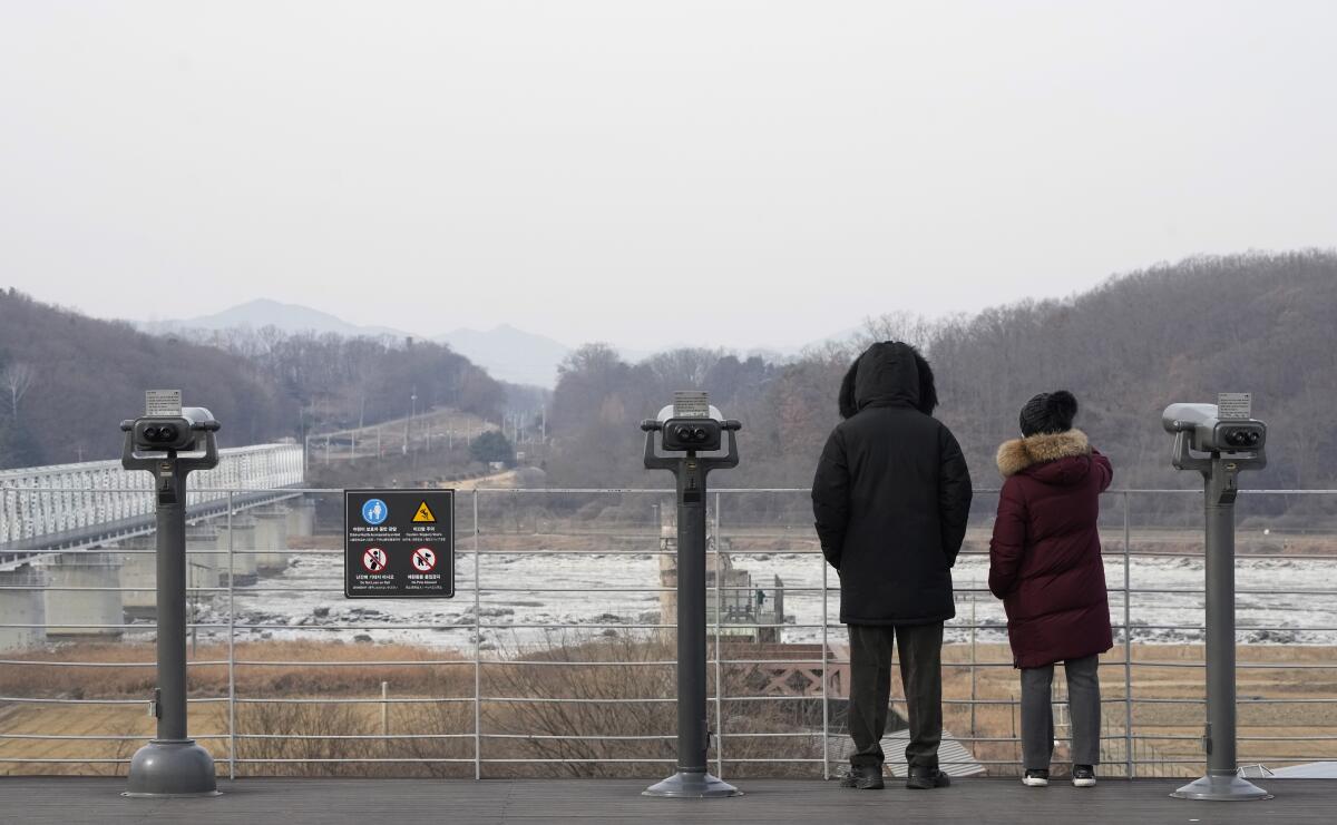 Two people on an observation deck look toward North Korea.