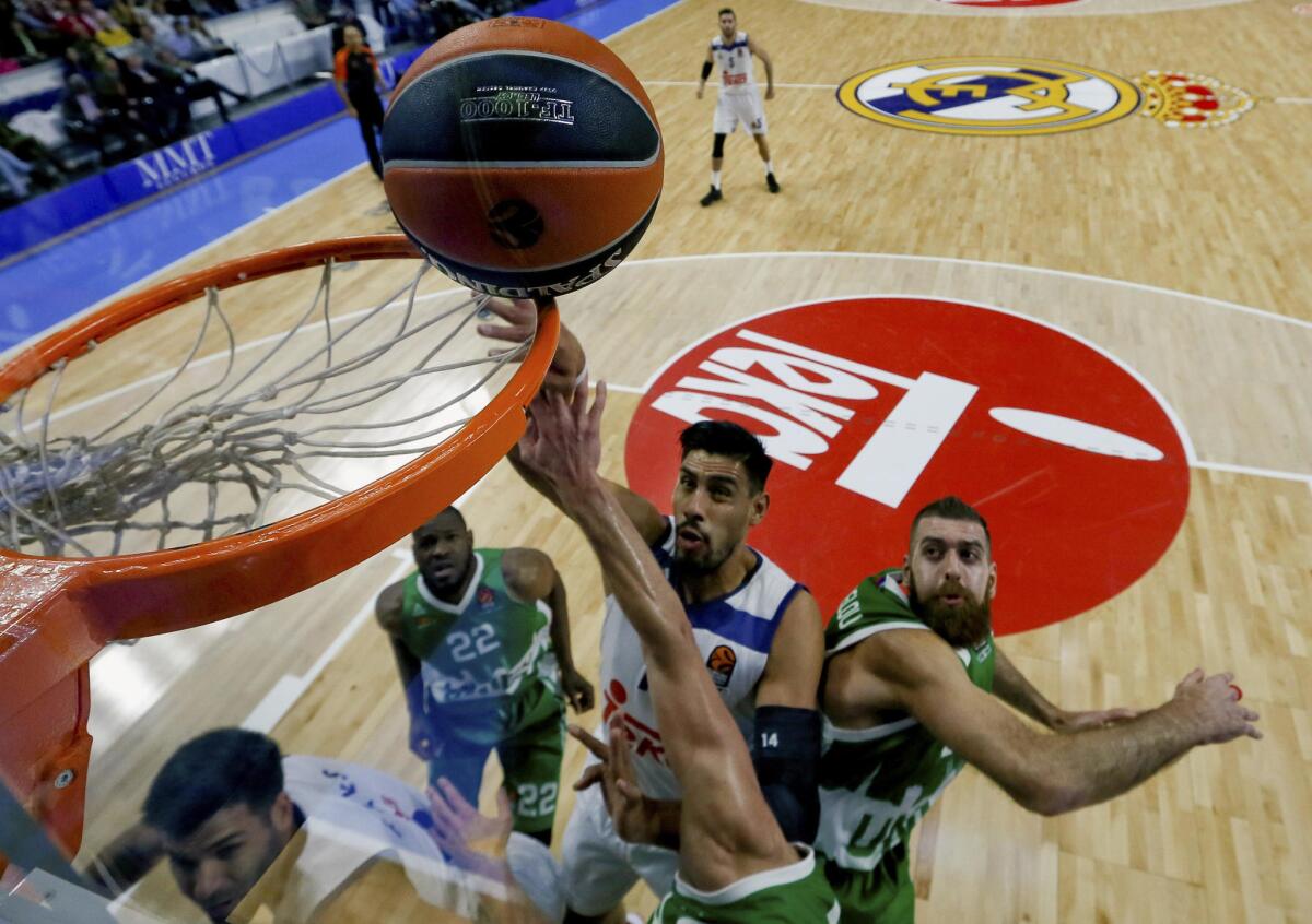 El pívot mexicano del Real Madrid Gustavo Ayón (c) encesta ante los jugadores del Unics Kazan durante el partido de la novena jornada de Euroliga que disputan en el Palacio de Deportes de Madrid.