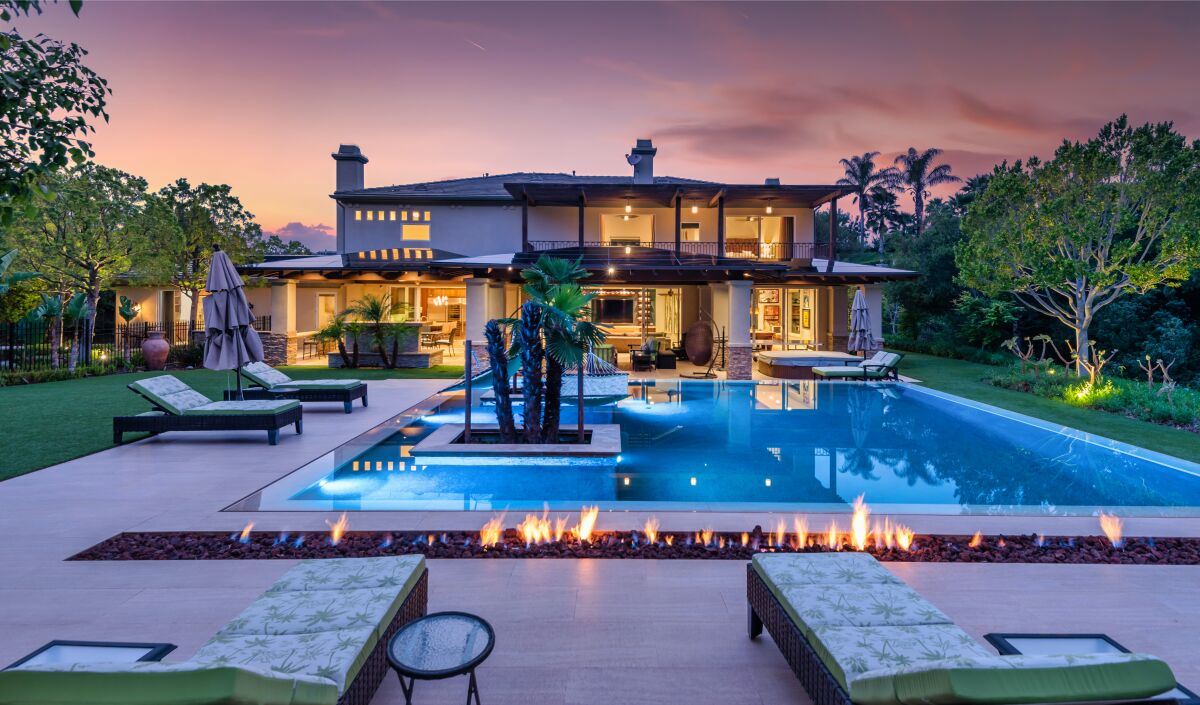 A pool and lawn furniture are seen behind a large home