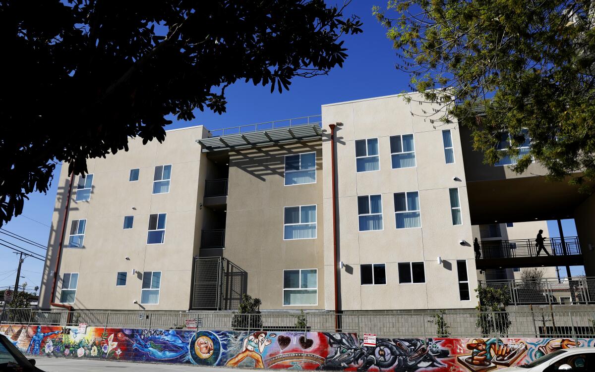 A multi-story building bordered by a fence and a colorful mural