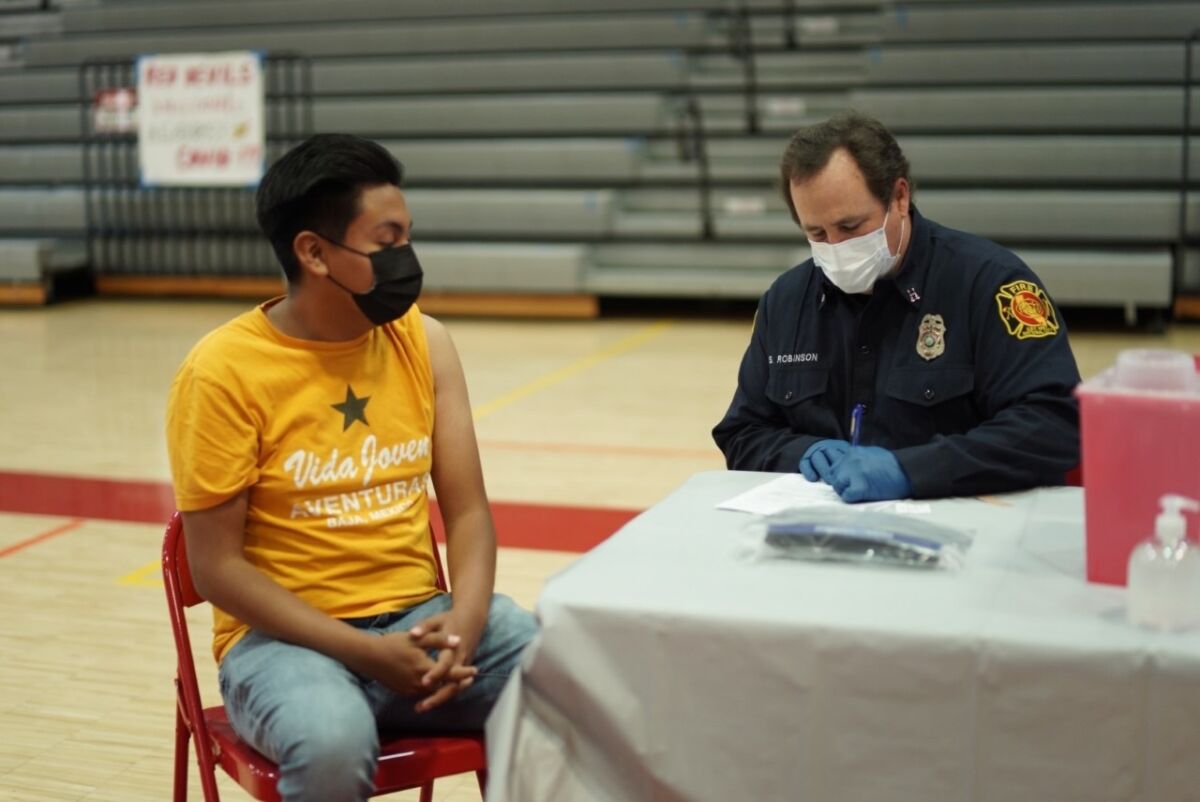Student Kevin Andres prepares to receive a Pfizer vaccine at a vaccination site hosted by his school, Sweetwater High