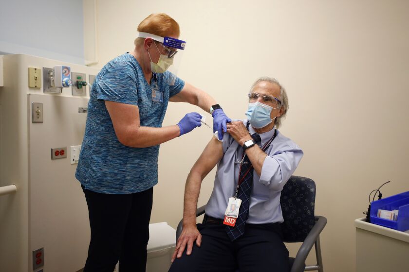SAN DIEGO, CA - DECEMBER 15: LVN Maureen Finnegan gives a Pfizer-BioNTech COVID-19 Vaccine shot to Dr. Bradley Bradley, Medical Director of Infectious Diseases at Rady Children's Hospital on Tuesday, Dec. 15, 2020 in San Diego, CA.(K.C. Alfred / The San Diego Union-Tribune)