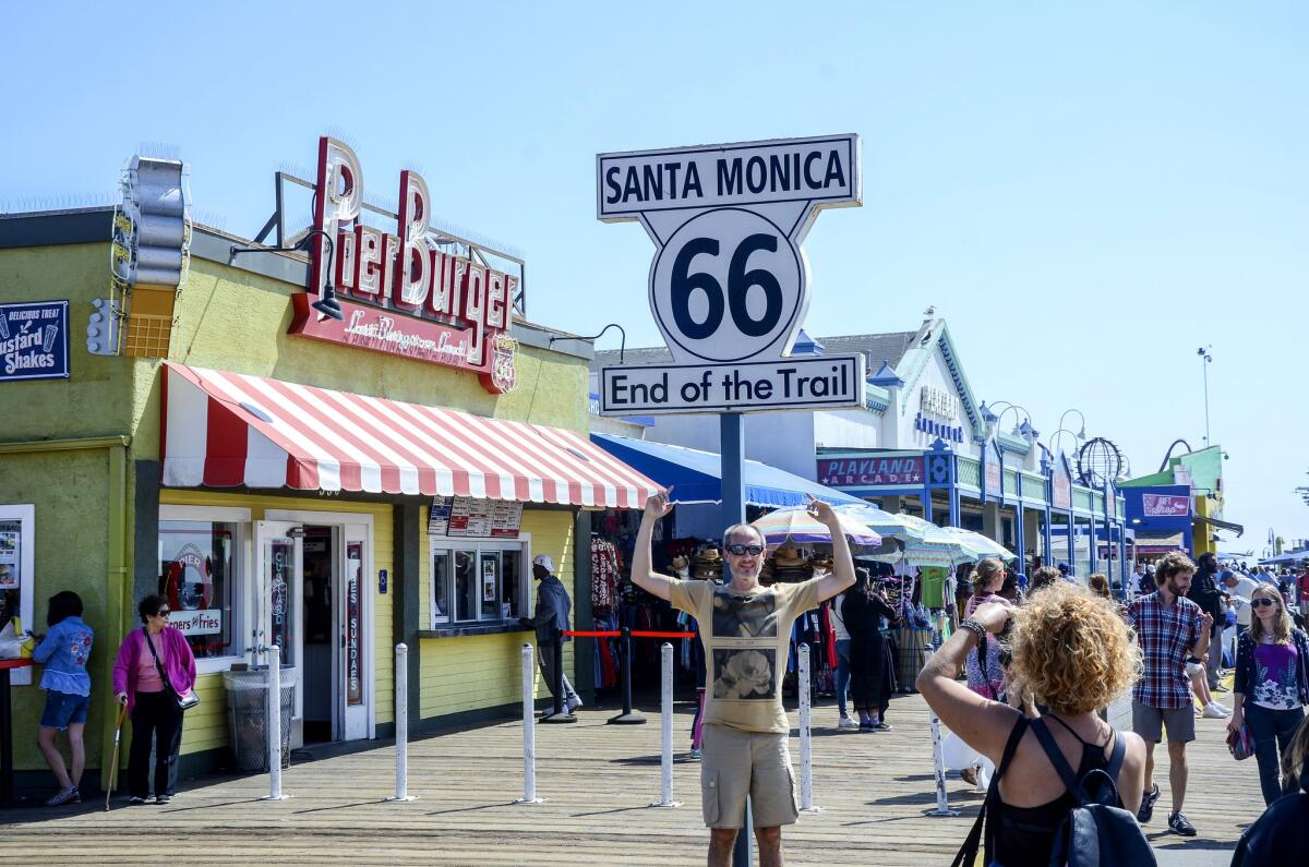 A man poses for a photo in front of the Route 66 sign on Santa Monica Pier. (Christopher Reynolds)