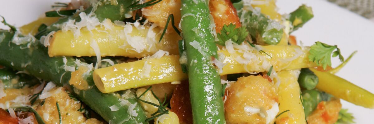 Close-up of a green bean salad with yellow wax beans and croutons on a plate. 