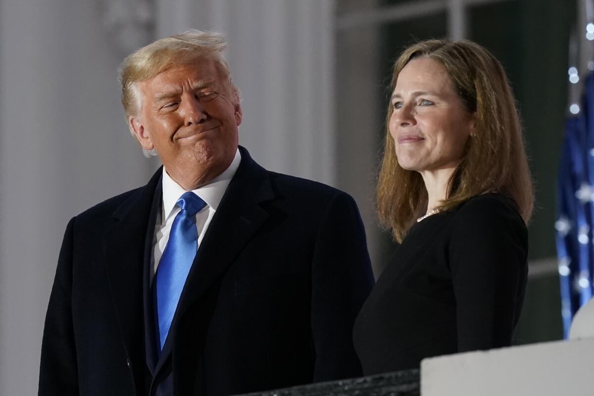 President Trump smiles as he stands alongside Amy Coney Barrett