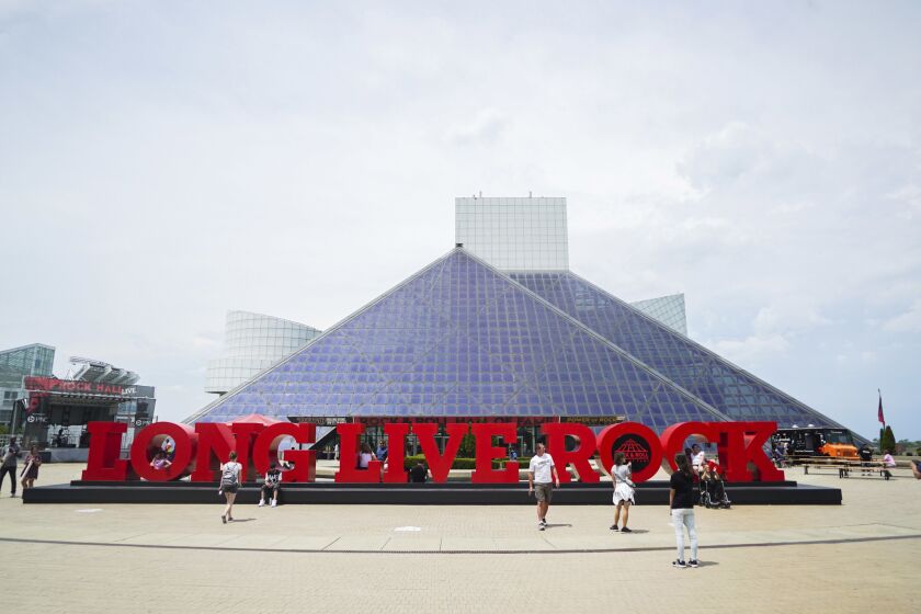 People pose for pictures outside the Rock and Roll Hall of Fame in Cleveland, Ohio, Thursday, June 29, 2017. A new exhibit called "Power of Rock" opened July 1 and gives fans a taste of what it's like to be a star inducted at the hall.