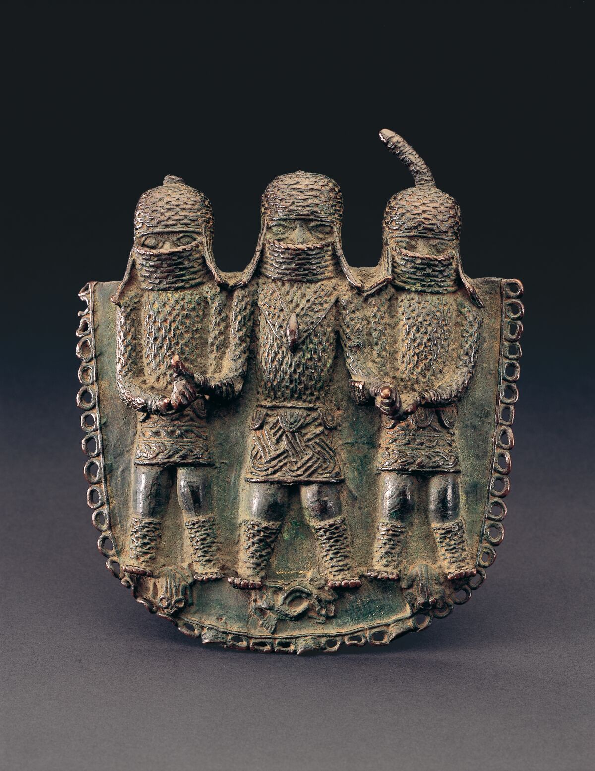 A cast copper alloy Benin pendant with figures of three people in relief