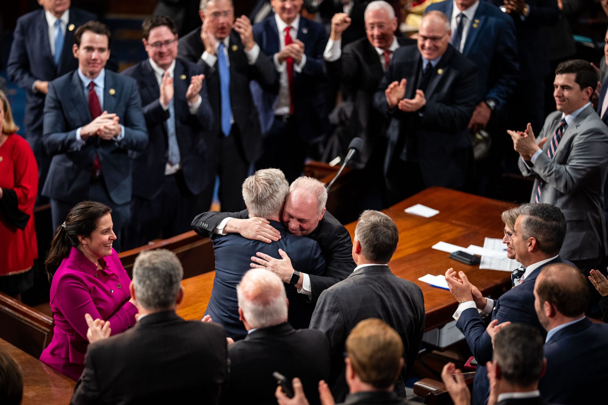 Two lawmakers hugging as others applaud