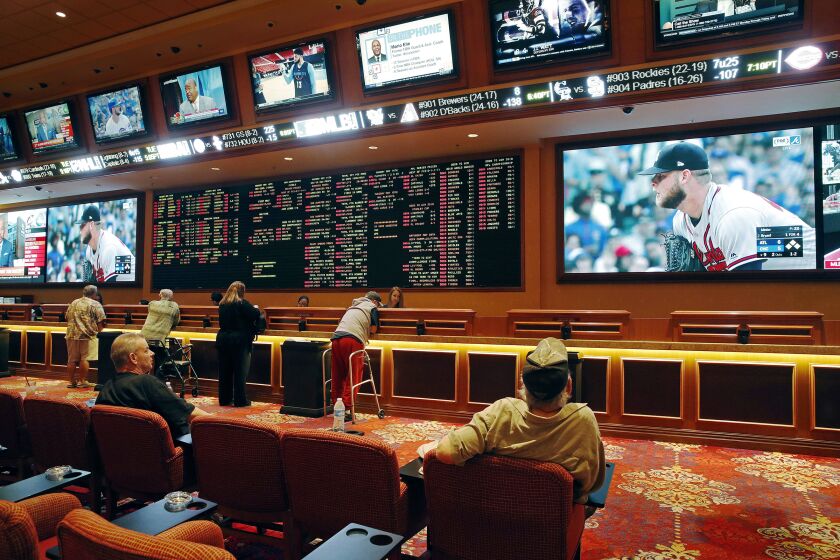 In this Monday, May 14, 2018 photo, people make bets in the sports book at the South Point hotel and casino in Las Vegas. Now that the U.S. Supreme Court has cleared the way for states to legalize sports betting, the race is on to see who will referee the multi-billion-dollar business expected to emerge from the decision. (AP Photo/John Locher)