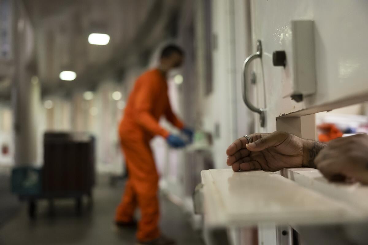 A man in solitary confinement holds his hand out of his cell. 