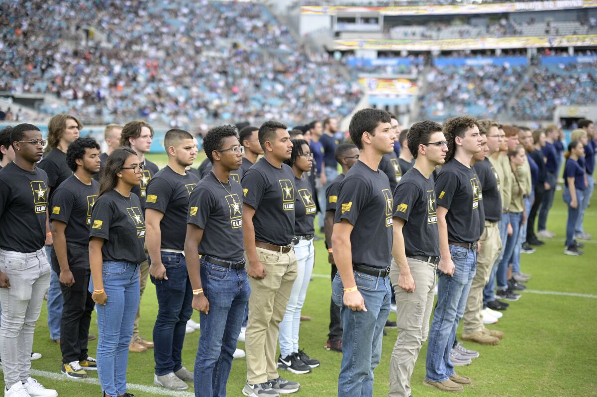 Military recruits stand in rows on a football field.
