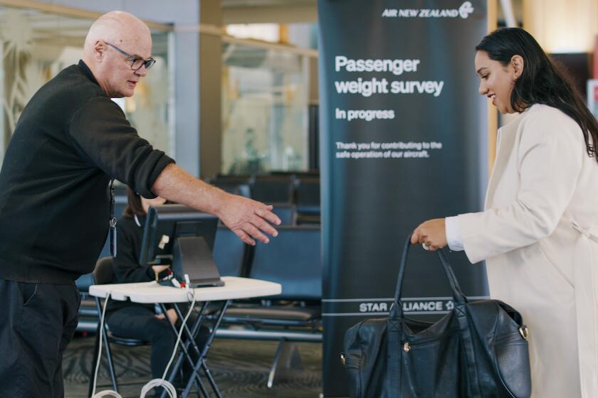 In this photo provided by Air New Zealand, a woman hands her bag to a staff member to be weighed ahead of a flight in Auckland, New Zealand, on May 29, 2023. New Zealand's national airline is asking people to step on the scales before they board international flights. Air New Zealand says it wants to weigh 10,000 passengers as part of a monthlong survey to better estimate the weight and balance of its planes. (Air New Zealand via AP)