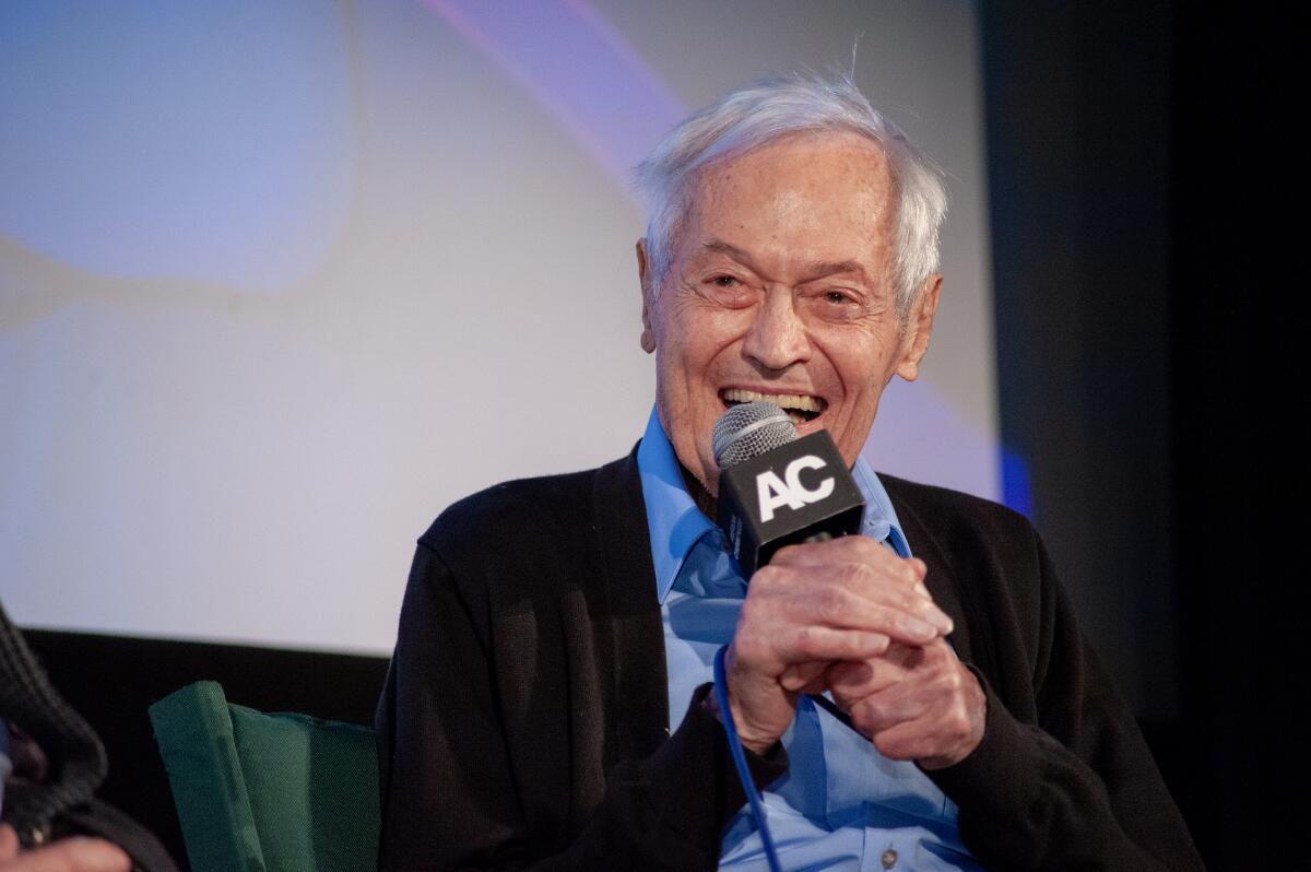 A smiling man speaks into a microphone.