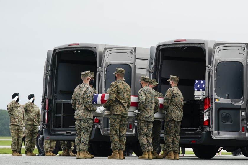 The body of a Marine is loaded into a vehicle.