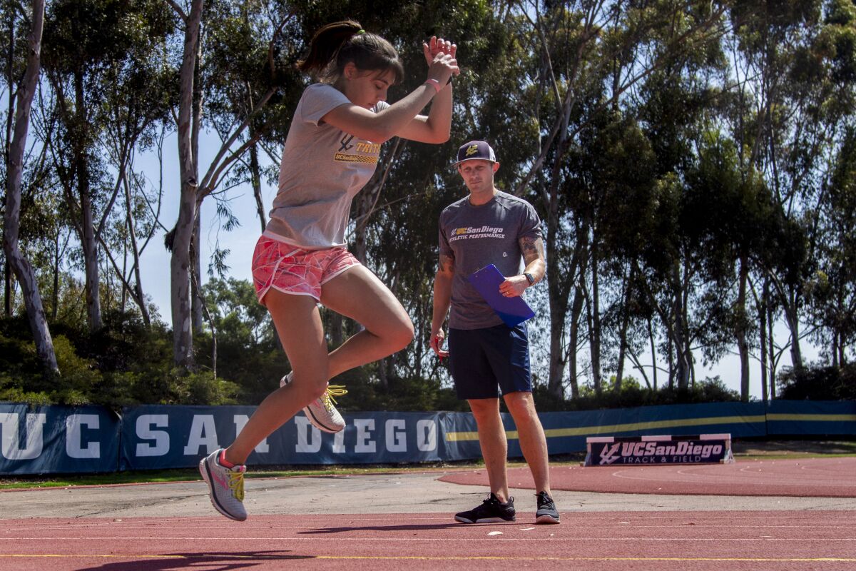 Jenna Mencarelli does track and field drills while performance coordinator Jon Gregory assesses her form at UC San Diego.
