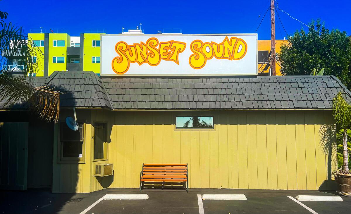 A yellow building with a bench outside under a sign that says Sunset Sound