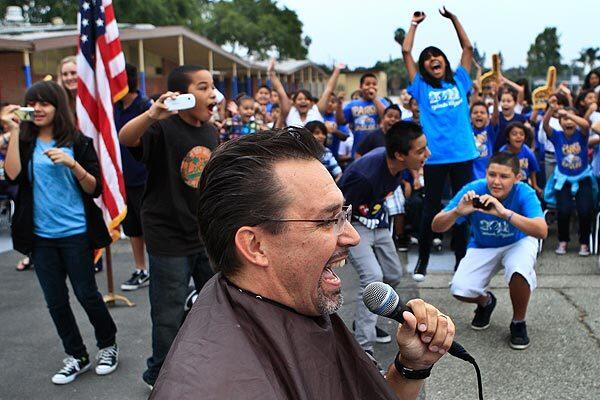 Delighted students at Sparks Elementary School in La Puente prepare for Principal Gregory O'Brien to have his head shaved. O'Brien was making good on his promise to sport a bald pate if the school attained a score of 855 on the state Academic Performance Index. The campus went one better and scored 856.